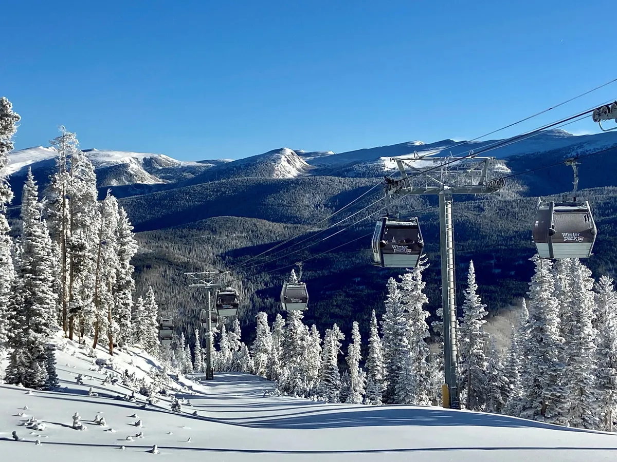 A scenic exterior shot showcasing ski lift gondolas gliding above snow-covered trees and a breathtaking mountain landscape, encapsulating the excitement and beauty of the ski resort environment.
